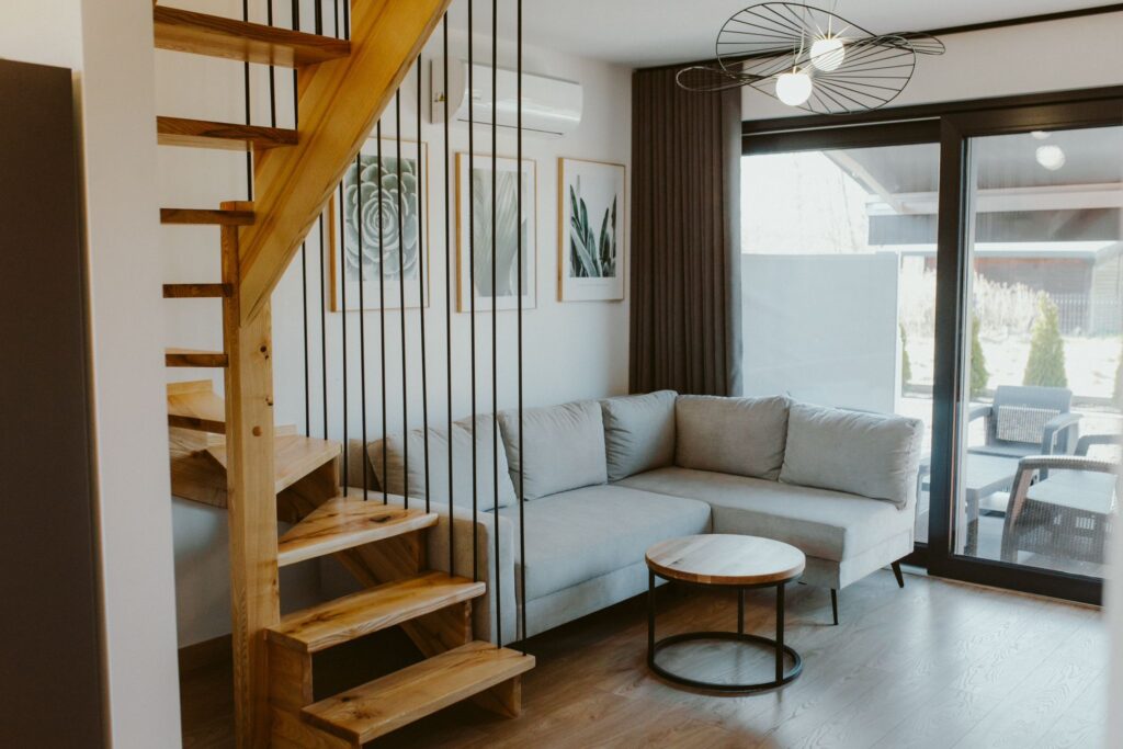 Nowoczesny salon z drewnianymi schodami i wyjściem na taras.